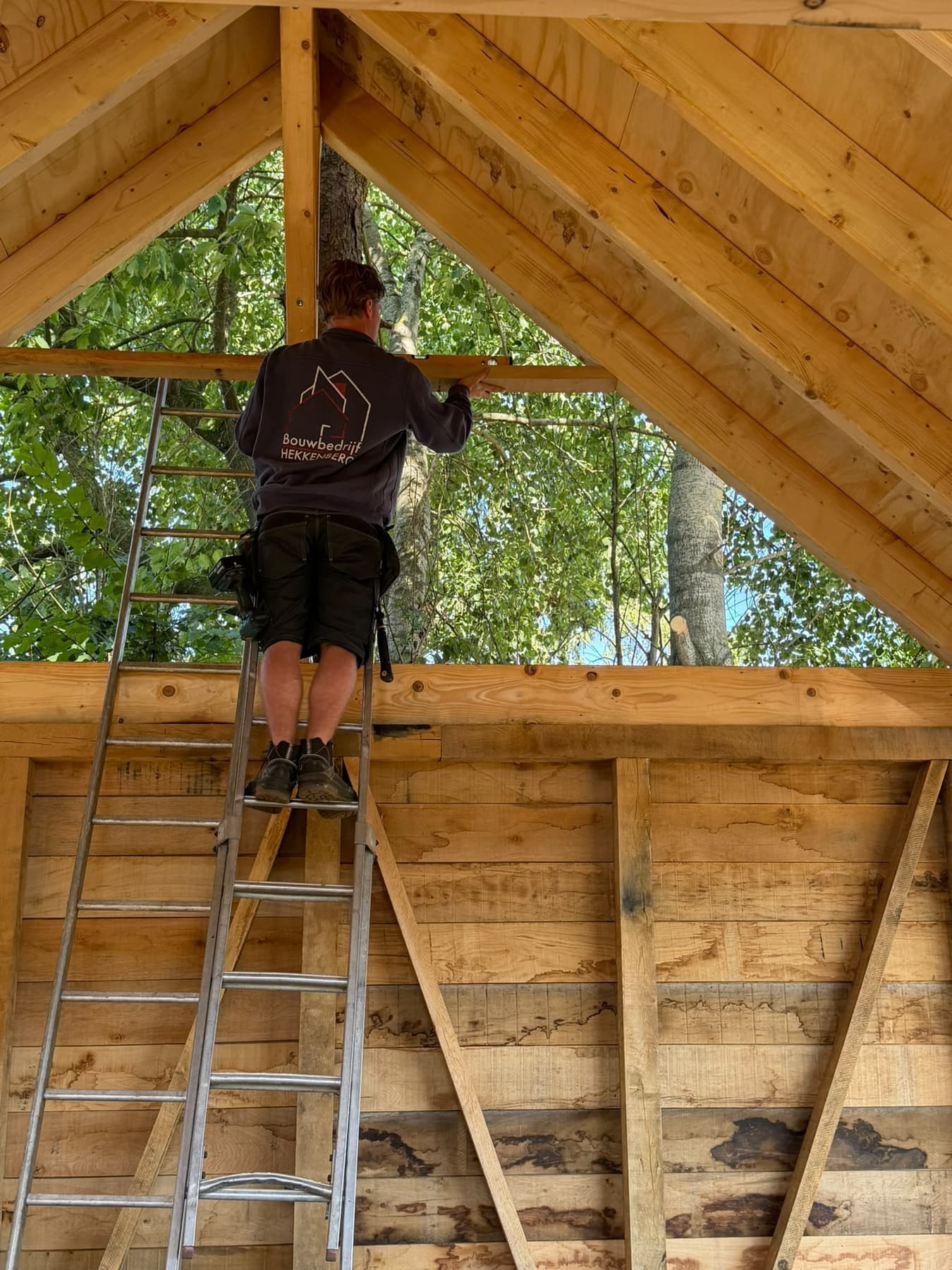 Timmerman van Bouwbedrijf Hekkenberg werkt aan een kapconstructie van een bijgebouw